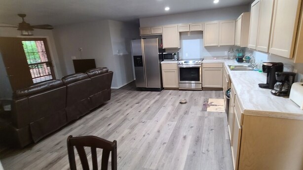 Eine kleine Küche mit Kühlschrank, Backofen, Mikrowelle und Holzschränken.