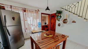 Una cucina con frigorifero in acciaio inox, tavolo da pranzo in legno e una scala con ringhiera metallica.