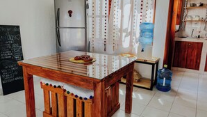 Una cucina con un tavolo di legno, un frigorifero, un erogatore d'acqua e un menu scritto su una lavagna.