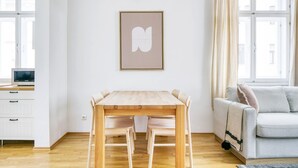 A modern living room with a wooden dining table, a sofa, and a framed artwork on the wall. - Modern Brigittenau 1BR w/ AC, Elevator, near Metro U4, by Blueground (Vienna)
