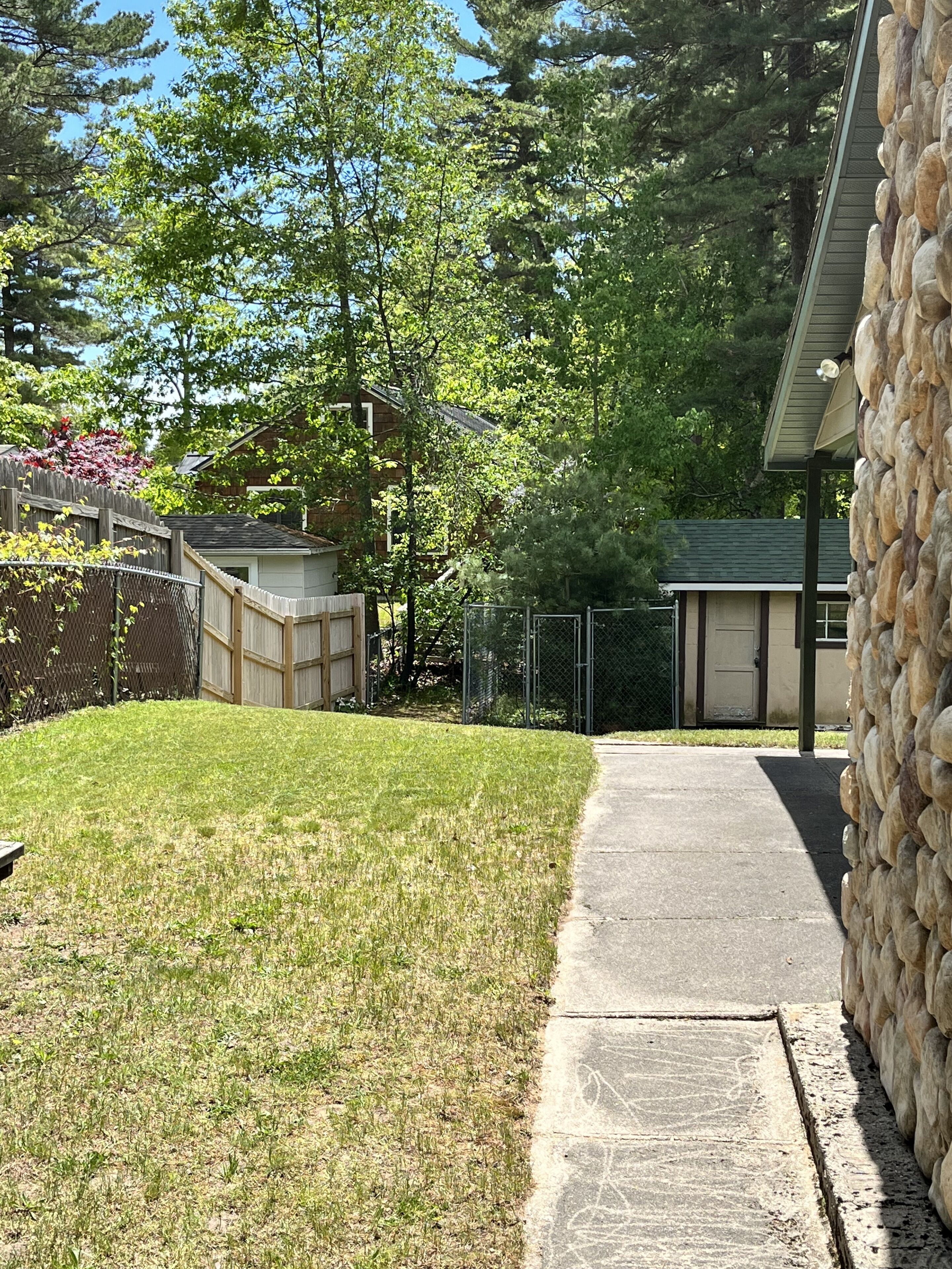 Ein Wohnhof mit Steinmauer, Holzzaun und Garage.