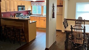 A spacious kitchen with wooden cabinets, a central island, and a dining area with a rustic wooden table and chairs. - Lake Huron Cottage (East Tawas)