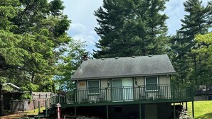 A two-story building with a balcony, a gravel driveway, and a stone wall. - Lake Huron Cottage (East Tawas)