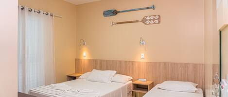 Habitación de hotel con dos camas, cabecero de madera, paleta en la pared y cortina.