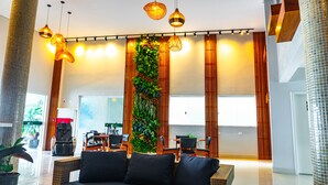 A modern lobby with a central vertical garden, wooden paneling, and a seating area with black sofas. - Ubatuba Praia Hotel (Ubatuba)