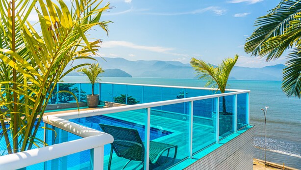 A glass-enclosed infinity pool with a view of the ocean and mountains. - Ubatuba Praia Hotel (Ubatuba)