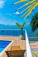 Zona junto a la piscina con vistas al océano y a las montañas.