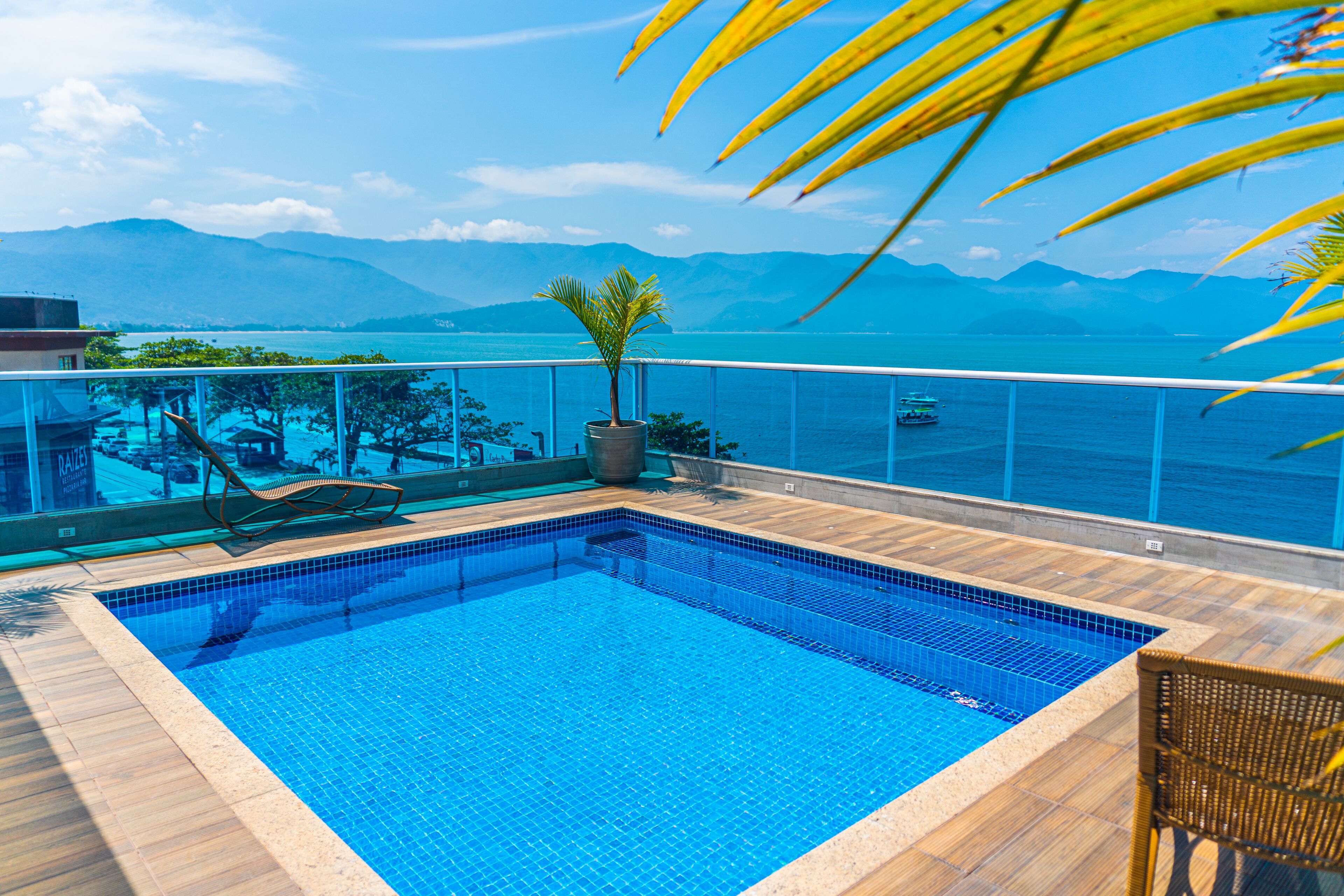 Une piscine rectangulaire aux carreaux bleus, entourée d’un sol en bois.