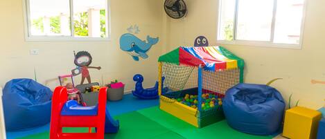 A playroom with a slide, ball pit, and colorful play structures.