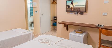 Habitación de hotel con dos camas, un televisor en la pared, un escritorio pequeño y una silla.