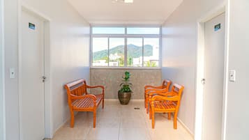A hallway with two wooden benches, a potted plant, and a large window with a view of buildings and hills.