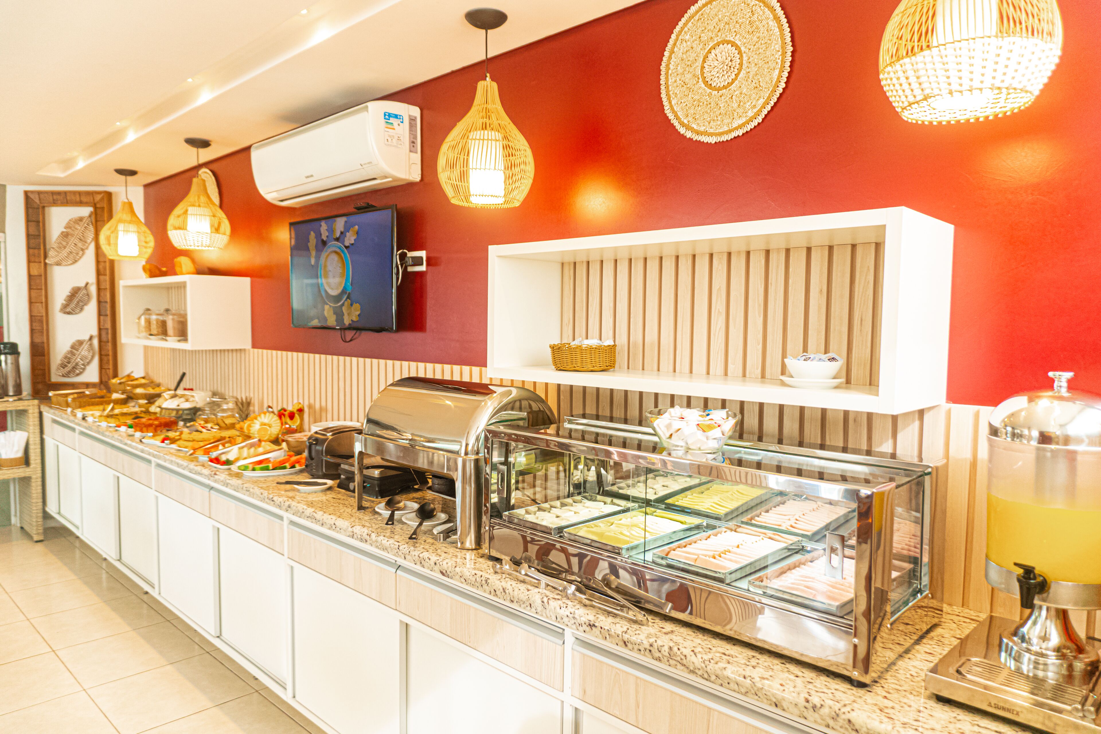 Un área de buffet con diversas opciones de comida, una máquina de café y un dispensador de jugo.