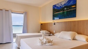 A hotel room with two beds, a large window with curtains, a painting of a beach scene, and a wooden headboard. - Ubatuba Praia Hotel (Ubatuba)