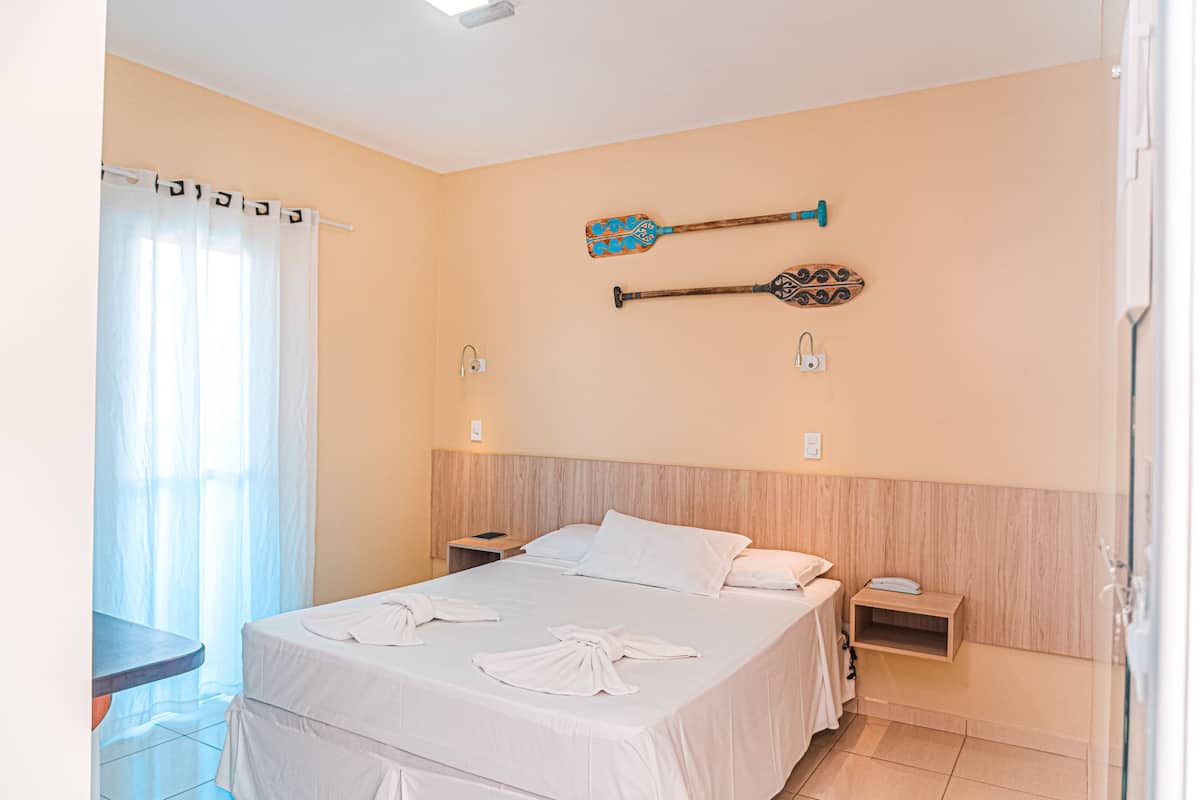 A hotel room with a bed, a nightstand, a desk, and a wall-mounted TV.