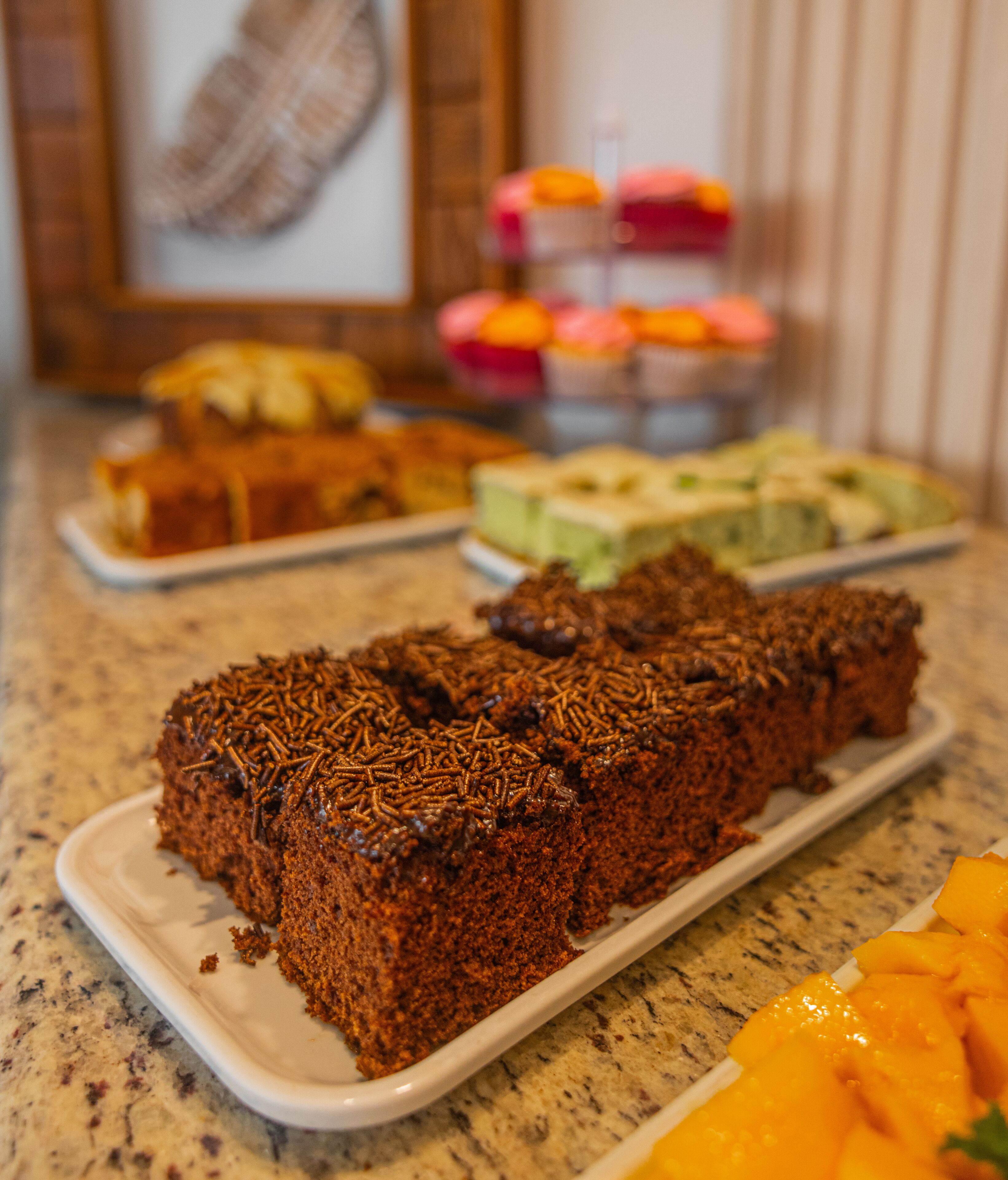 A dessert table with various cakes and a fruit arrangement.