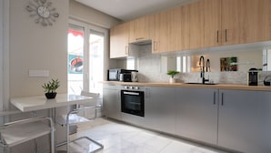 Une cuisine moderne dotée d’appareils électroménagers en acier inoxydable, de meubles en bois et d’un sol en marbre.