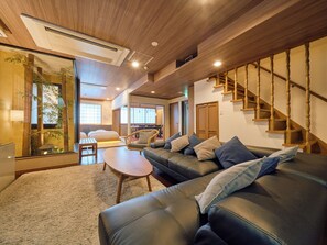 Un salon moderne avec un canapé en cuir, un escalier en bois et un coin repas.
