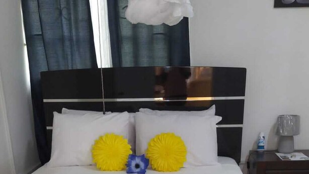 Een opgemaakt bed met een witte spreidek en een decoratieve gouden loper.
