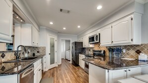 A modern kitchen with white cabinetry, a granite countertop, and a stainless steel refrigerator.