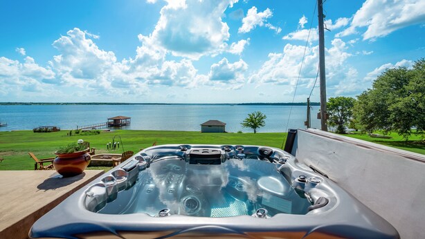 A hot tub with a view of a lake and a gazebo in the background.