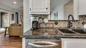 A modern kitchen with granite countertops, a coffee maker, and a sink.