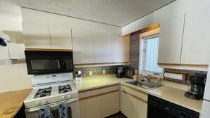 A compact kitchen with white cabinets, a microwave, stove, sink, and dishwasher. - Private 2Bd 2Bath - Sleeps 5/6 Town home In Stowe VT - 15min From The Mountain (Stowe)