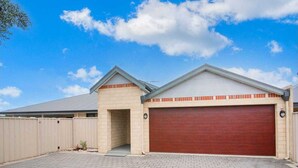 A two-car garage with a red door, a small entryway, and a covered driveway. - Central 3 Bed home with pool, EV Charger and unlimited free Wi-Fi (Busselton)