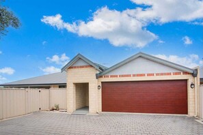 Set against a clear sky, this two-story building features a brick and siding exterior with a prominent garage door.
