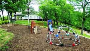Ein Spielplatz mit Schaukel, Rutsche und Klettergerüst.