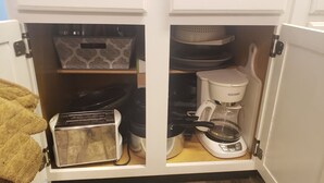 Ein Küchenschrank mit einem Toaster, einer Kaffeemaschine und einer Regalanordnung mit Geschirr.