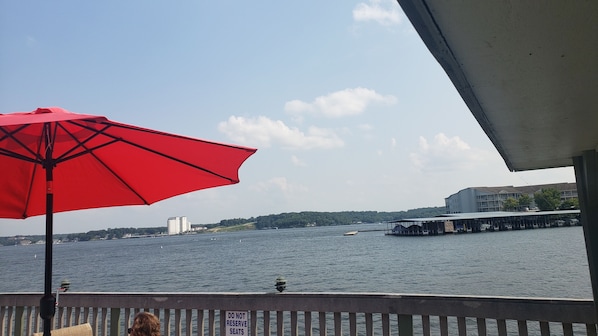 Une vue sur le bord de l’eau, avec un parasol rouge, un panneau d’avertissement et un bâtiment situé de l’autre côté.