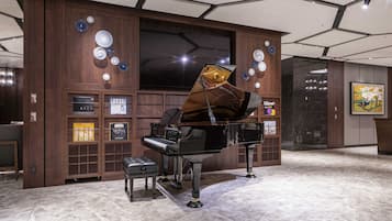 Un magnifique piano à queue trône dans un hall spacieux, agrémenté d’un mur lambrissé en bois, d’un grand téléviseur à écran plat et d’un sol en marbre.