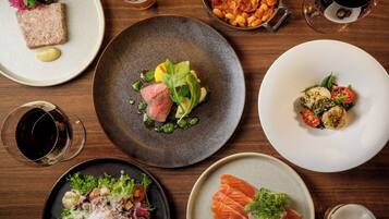A variety of dishes on a wooden table, including a salad, steak, and seafood.