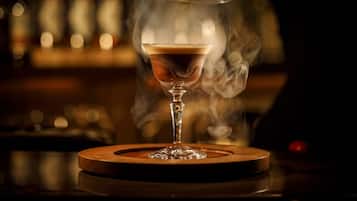 Una copa de martini con un efecto ahumado sobre un posavasos de madera.