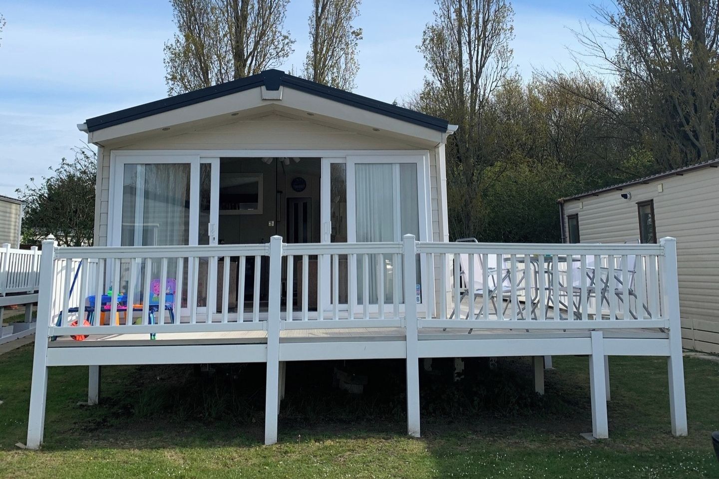 A mobile home with a porch and a fenced deck.