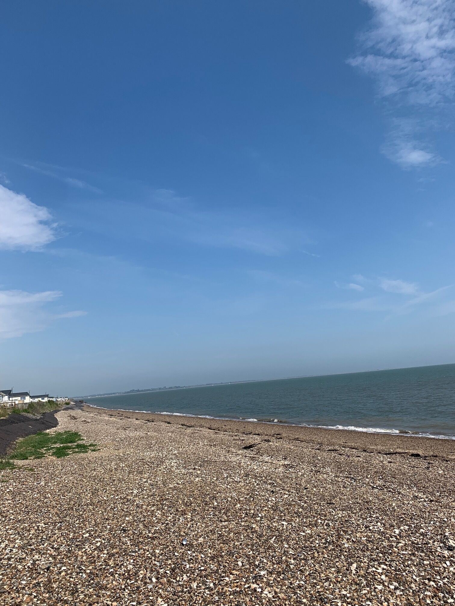 A pebble beach with a clear sky and calm sea.