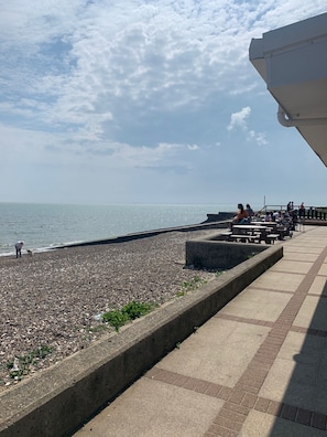 A pebbled beach with a clear sky and calm sea.