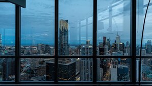 A cityscape through large windows, featuring modern high-rise buildings and a clear sky. - Spacious 3 Bedroom with stunning city view (Toronto)
