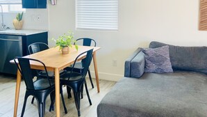 Un espacio habitable moderno con una mesa de comedor de madera, sillas negras, un sofá gris y una alfombra estampada.