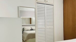 A bedroom with a bed, a wardrobe, and a mirror. - Hollywood Apartments (Yabucoa)
