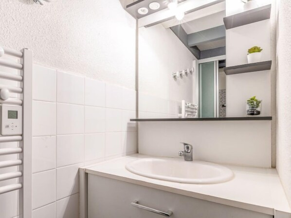 A modern bathroom with a white sink, a mirror, and a towel rack.