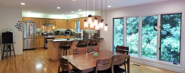A modern kitchen with wooden cabinets, stainless steel appliances, and a large island with seating. - Rushing Water, Hot Tub, Big Deck, Firepit, Hiking, National Forest & Wi-Fi (Franklin)