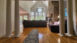 A spacious living room with a large sectional sofa, a stone fireplace, and a skylight.