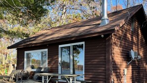 A wooden cabin with a chimney, a picnic table, and a grill area. - FALL DATES OPEN! Lakeside Cabin - Sandy Beach & Amazing Lake View! (Hillman)