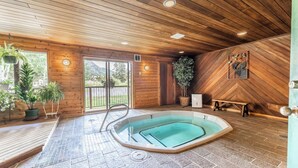 A wooden interior with a hot tub, potted plants, and a view of the outdoors. - Snowdance 203c by Summit County Mountain Retreats (Keystone)