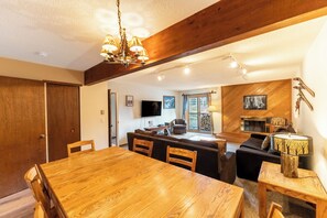 Ein Holzespeisesaal mit Stühlen, eine Couch, ein Fernseher und ein Kamin in einem gemütlichen Wohnbereich.
