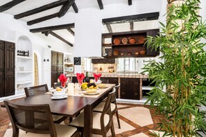 A dining area with a wooden table, chairs, and a large potted plant. - Pool Villa Jazmin, Marbella, Spain (Marbella)