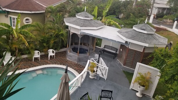 Et tagområde med pool, jacuzzi, liggestole og en pergola.