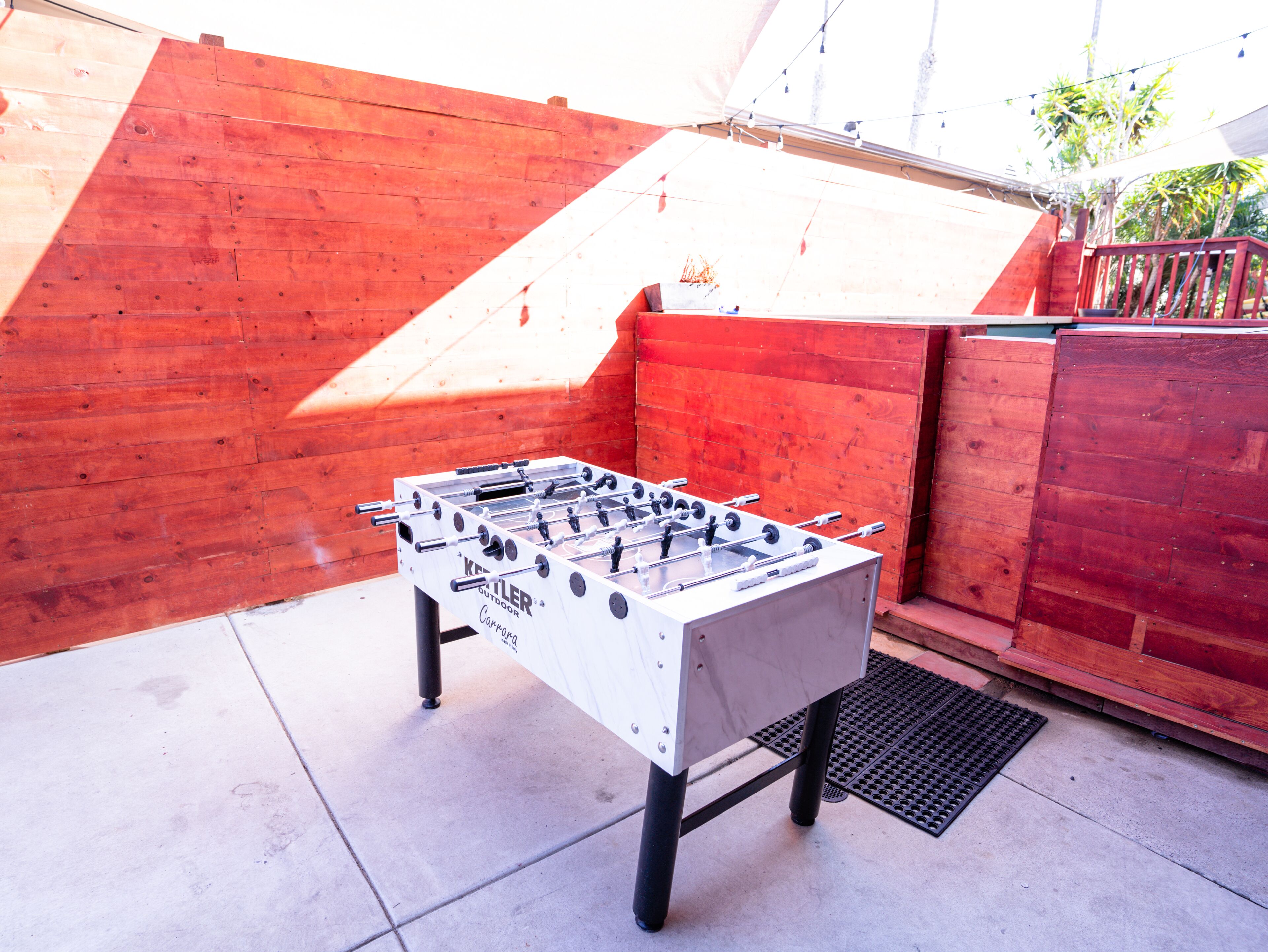 An outdoor foosball table set against a wooden backdrop.