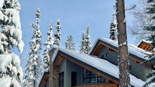 A modern two-story lodge with a stone facade and large windows, surrounded by snow-covered trees. - Large Ski-In / Ski-Out Timber Frame House, Open Concept, New Hot Tub! (Golden)